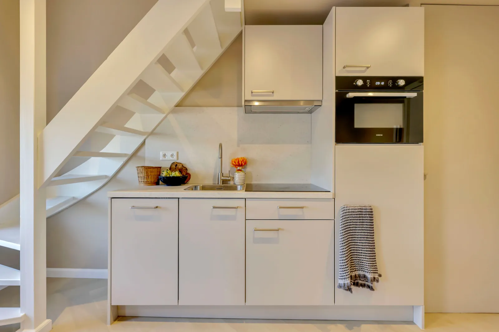 Compacte keuken onder de open trap in de modelwoning