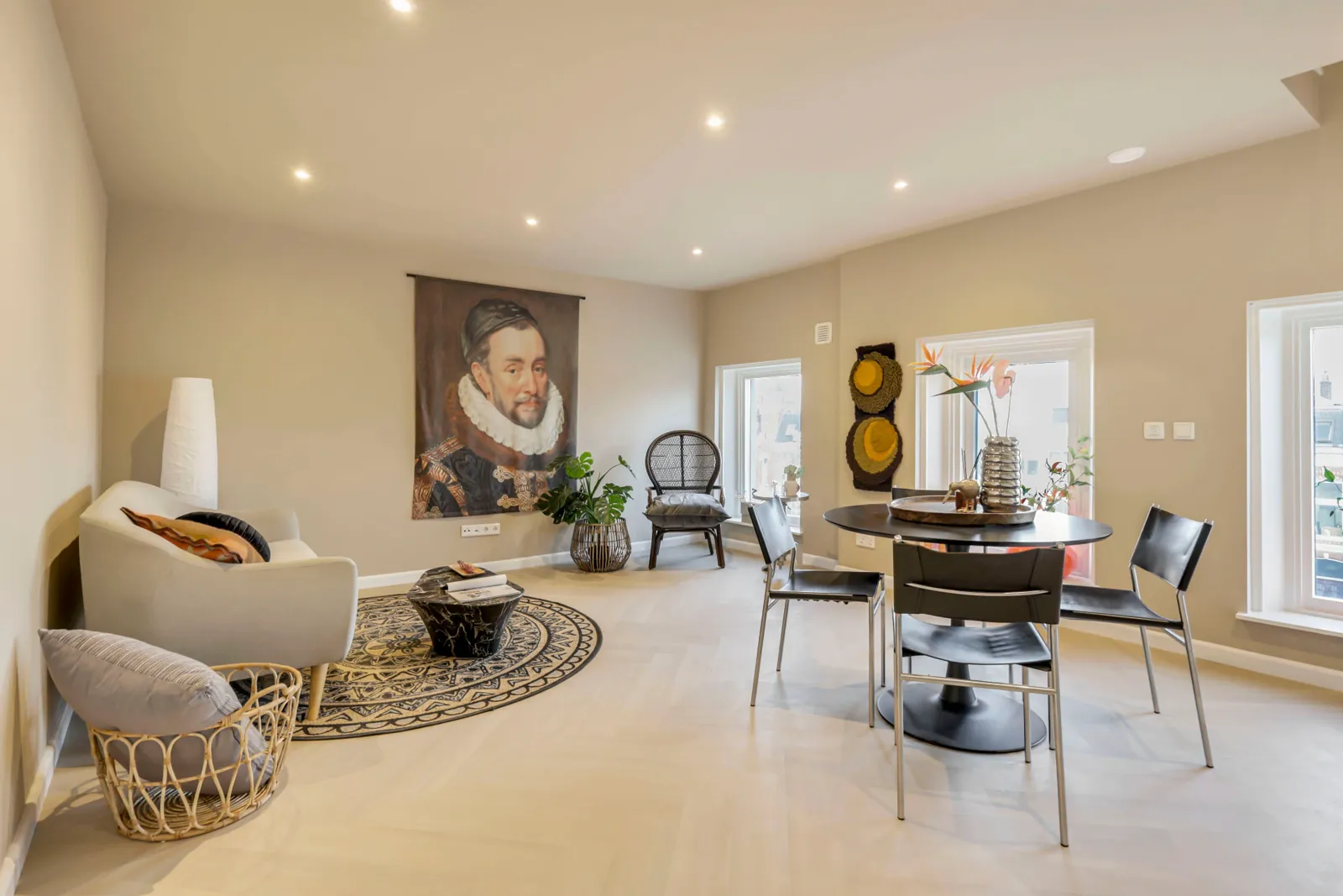 Woon- en eetkamer van de turnkey modelwoning met wandportret en rond tapijt